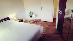 A bedroom with a bed, bedside table, lamp, and a small potted cactus on a white chair. - Magnificent 18th century mill (eccica suarella)