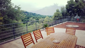 A terrace with wooden furniture and a view of a mountainous landscape. - Magnificent 18th century mill (eccica suarella)