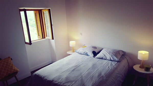 A bedroom with a bed, two bedside tables with lamps, a window, and a chair. - Magnificent 18th century mill (eccica suarella)