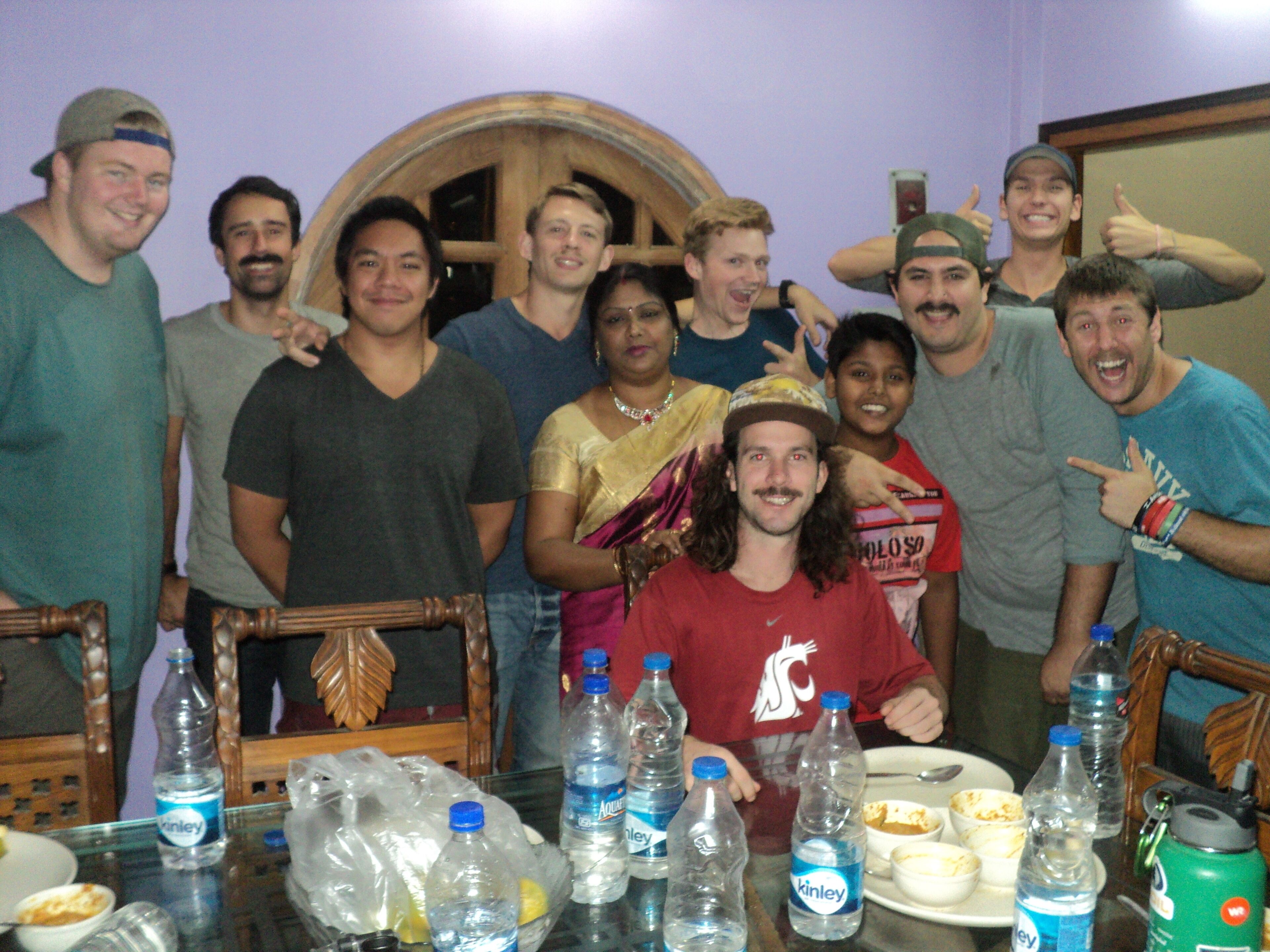 A group of people seated around a table with water bottles and food containers.