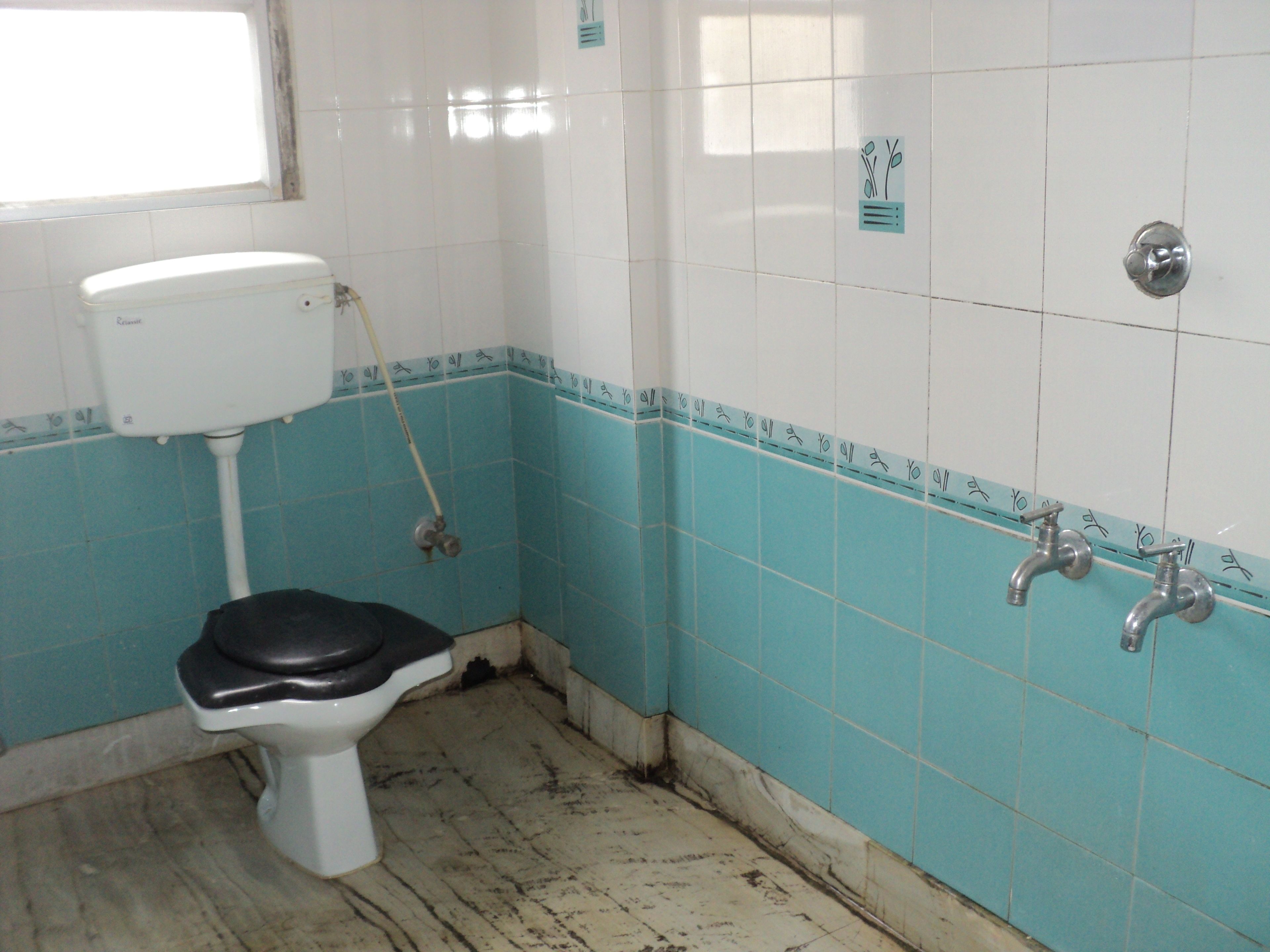 Et badeværelse med toilet, bruser og håndvask.