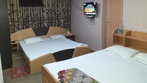 Quarto de hotel com duas camas, televisão presa na parede e guarda-roupa de madeira.