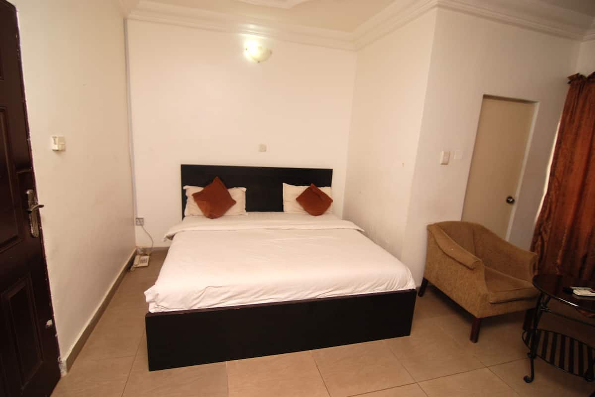Un dormitorio con cama, una silla y una puerta.