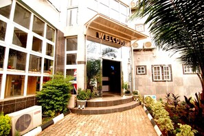 A building with a 'WELCOME' sign, large windows, and a paved entrance area with potted plants. - Silverland Hotel and Suites (Abuja)