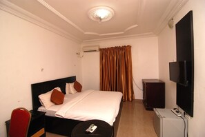 Une chambre d’hôtel équipée d’un lit, d’une télévision, d’une petite armoire et d’un appareil de climatisation.