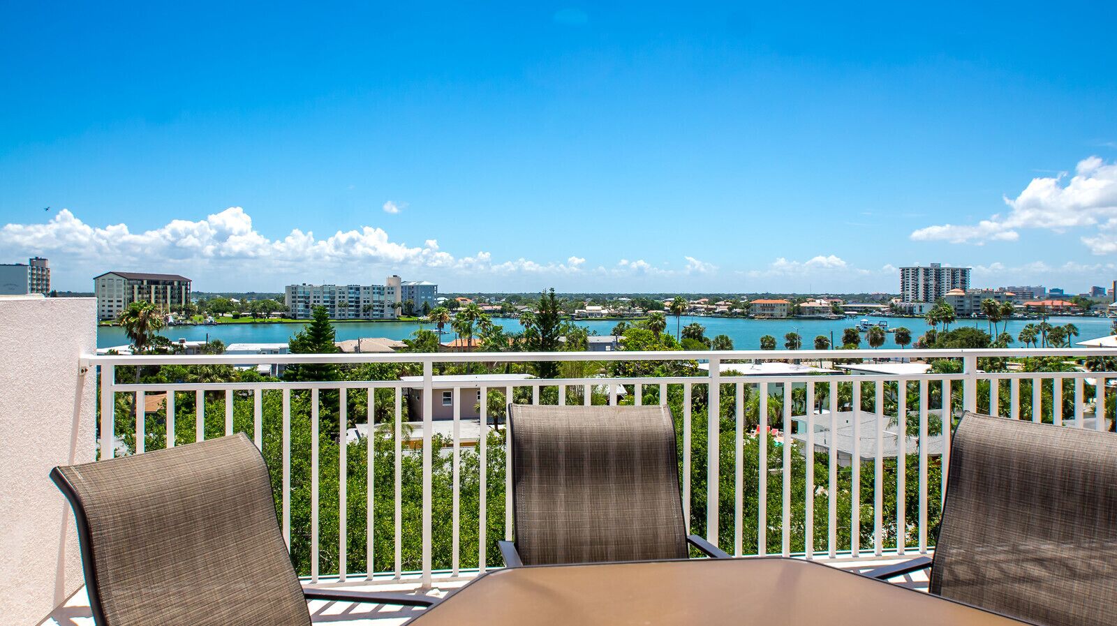 Un balcon avec un espace salon extérieur et une vue sur un port de plaisance et des immeubles.