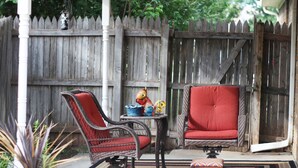 A patio with wicker chairs and a small table, surrounded by a wooden fence and potted plants. - Clean, Light, Centrally Located, Quiet Neighborhood (Amarillo)