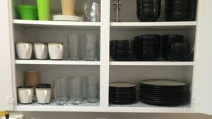 A kitchen with white cabinets, a granite countertop, and various kitchenware including cups, bowls, and plates. - Clean, Light, Centrally Located, Quiet Neighborhood (Amarillo)