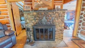 A log cabin interior with a stone fireplace, wooden walls, and a cozy seating area. - Republic Island -Summer Paradise – Your Private Island Awaits! (Republic)