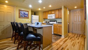 Una cocina con armarios de madera, un refrigerador blanco, un microondas y una mesa de comedor de madera con sillas.