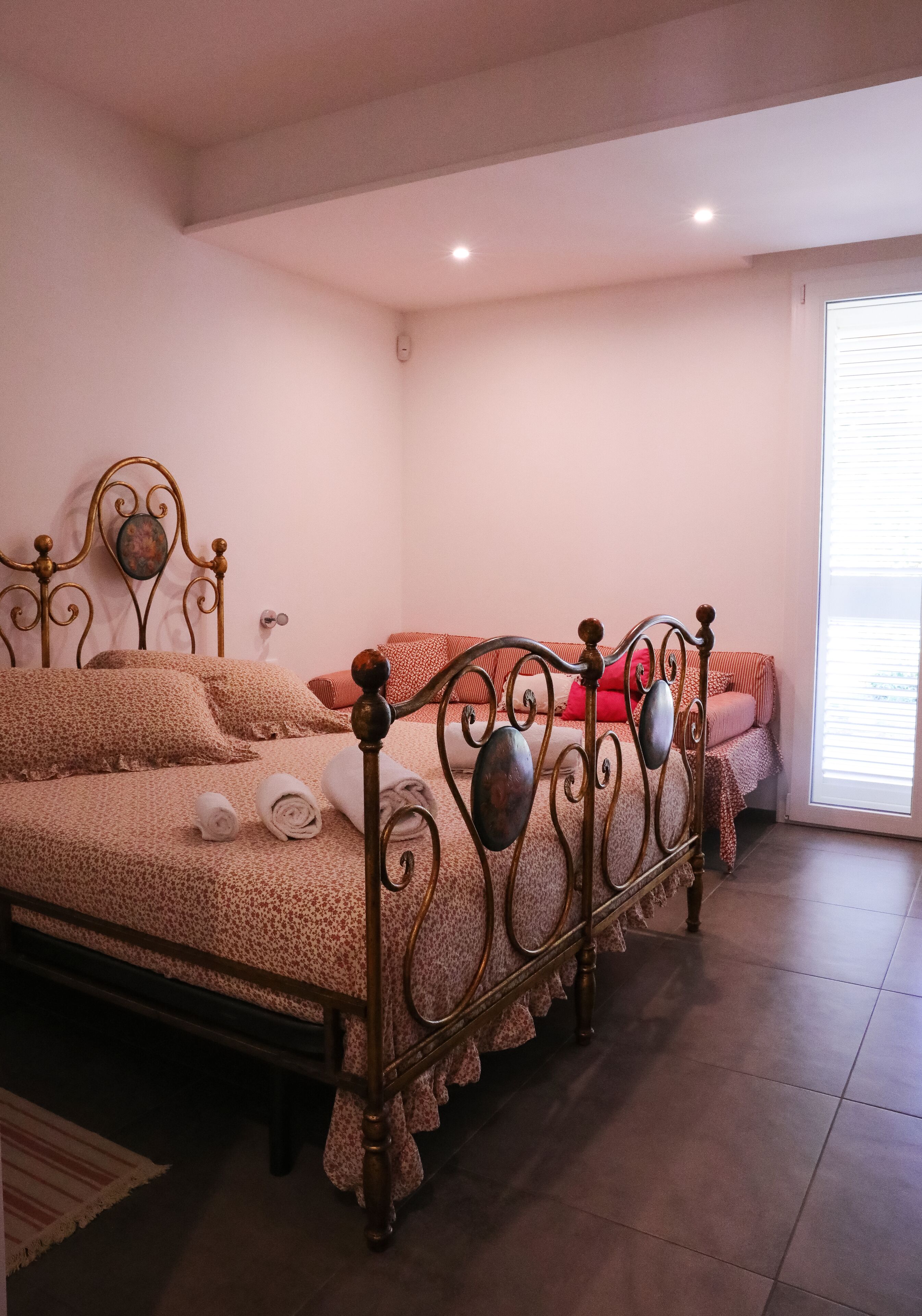 Een slaapkamer met een bed, kussens en een raam.