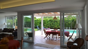 Un interno moderno con zona pranzo, piscina e porta vetrata che si apre su un giardino.