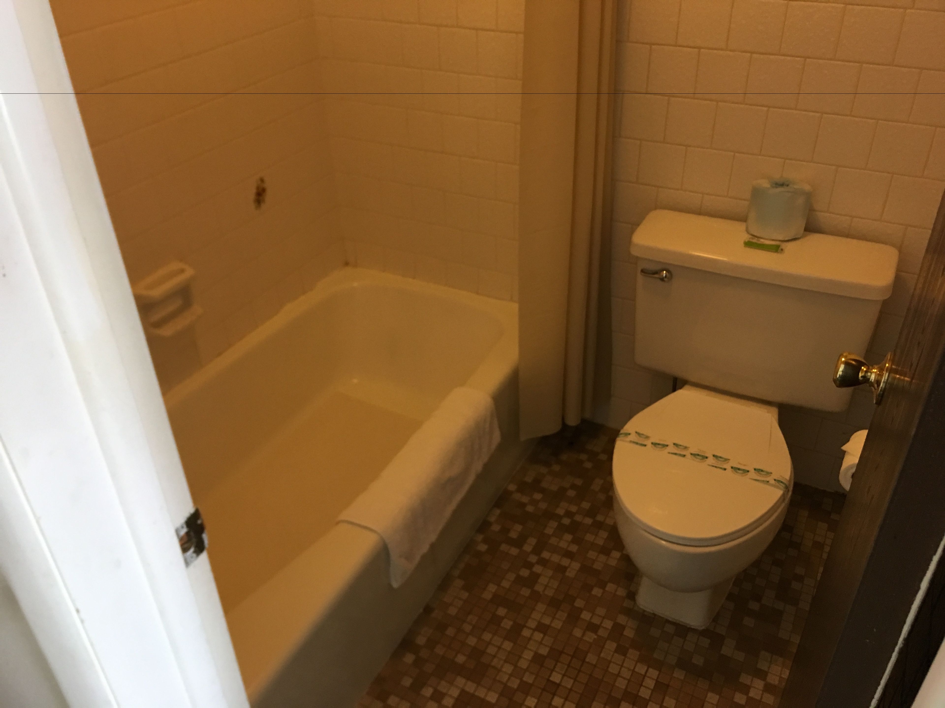 Un baño con bañera, inodoro y suelo de baldosas.