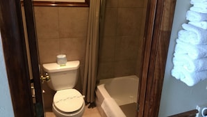 A bathroom with a toilet, a bathtub, and a shower. - Flag's West Motel (Downey)