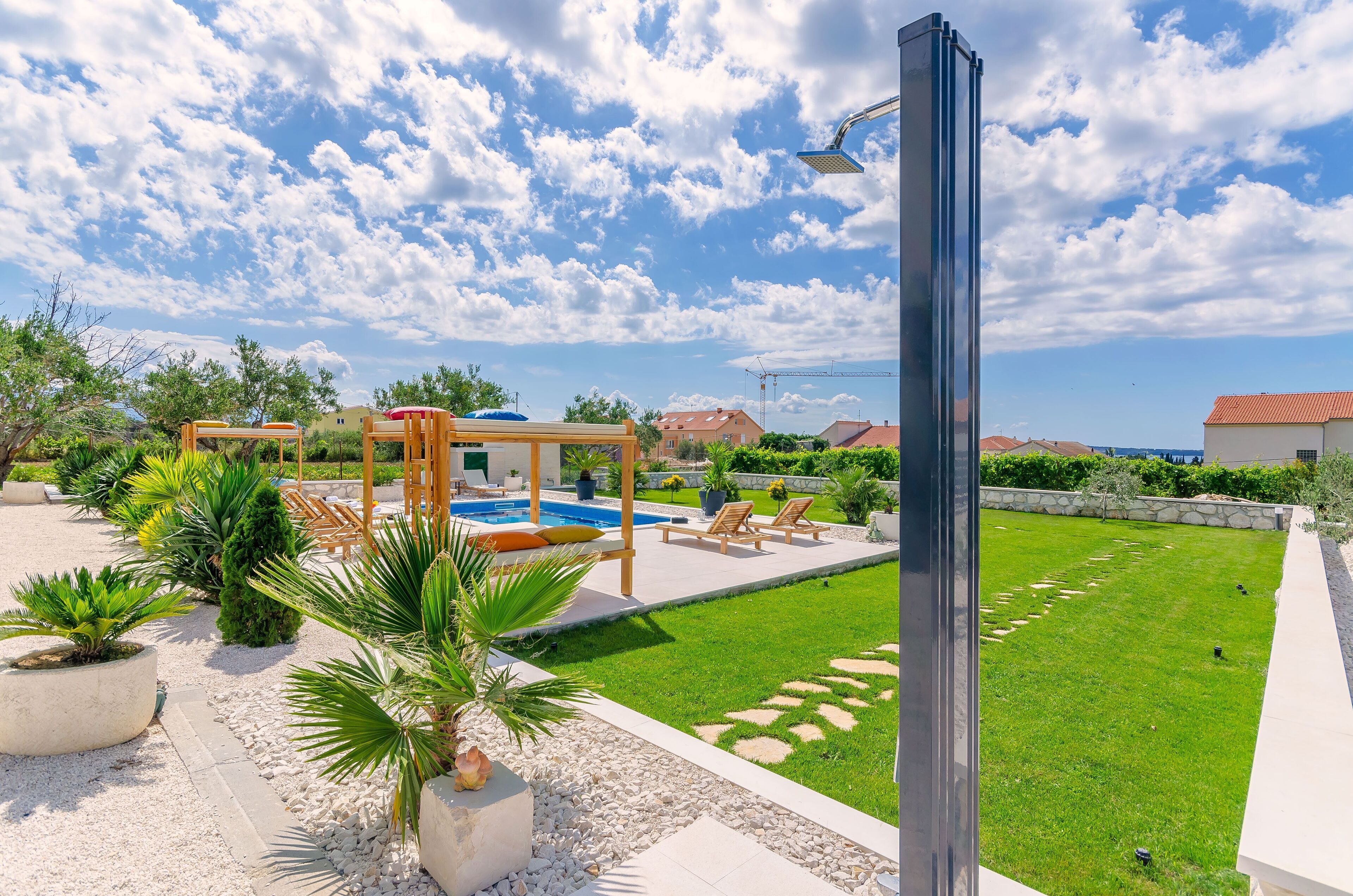 Un patio trasero con piscina, sillas de descanso y una pérgola.