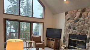 A spacious living room with a stone fireplace, a large flat-screen TV, and a comfortable seating area.