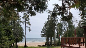 A wooden deck overlooking a beach with a view of the ocean and dense trees.