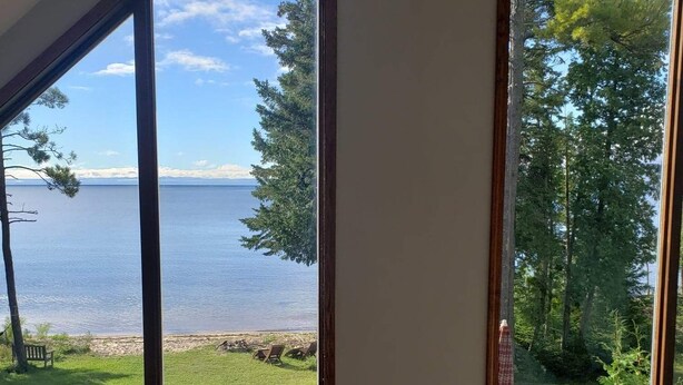 A room with large windows offering a view of a lake and forest.