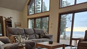 A spacious living room with a large sofa, a coffee table, and a view of the ocean through large windows.