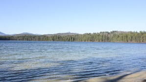 A lake with a forested shoreline and distant mountains. - Newly Renovated Rustic Cabin   (Tamworth)