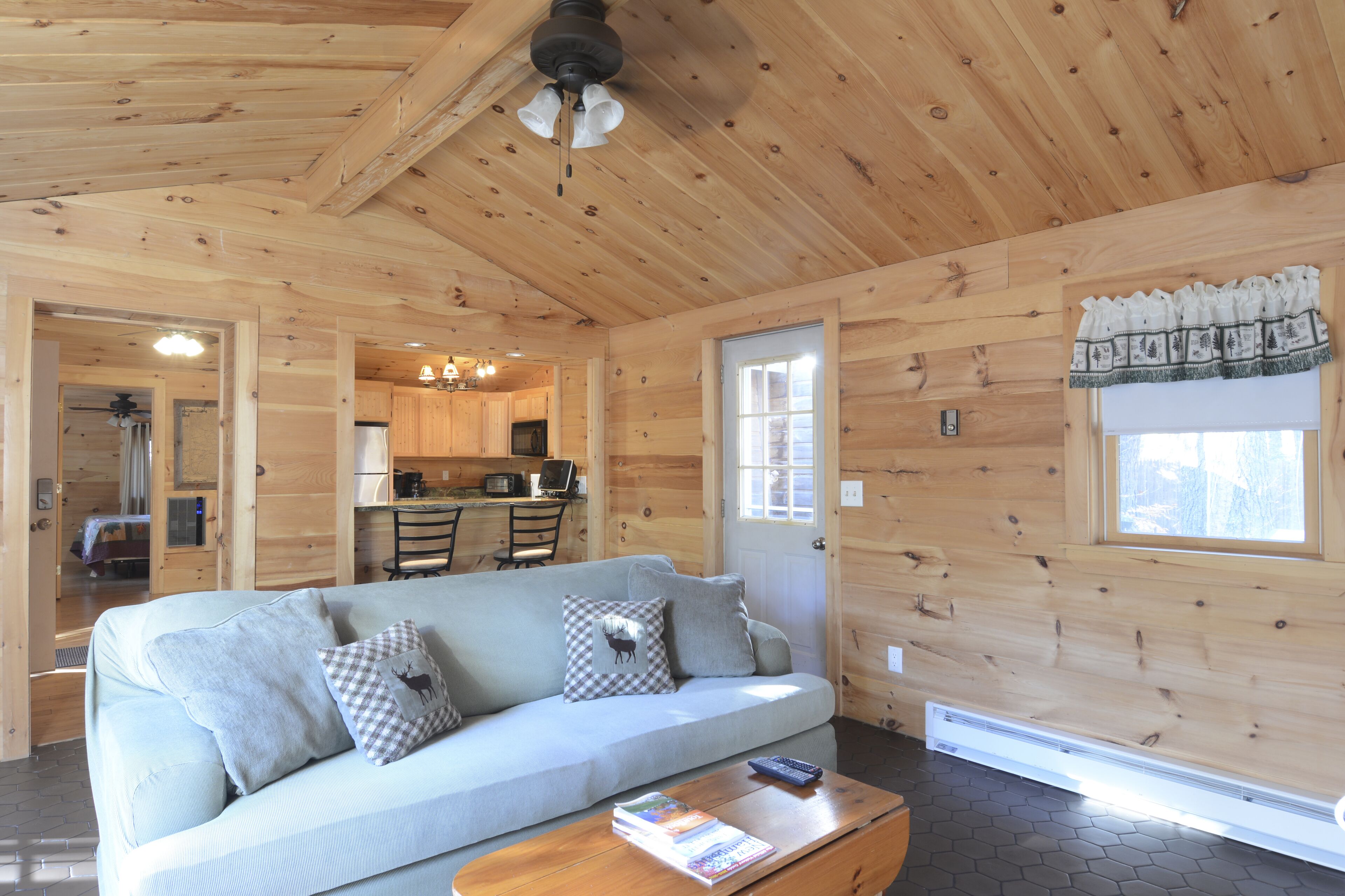 A wooden interior with a sofa, a dining table, and a kitchen area.