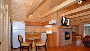 A cozy cabin interior with a kitchen, dining area, and fireplace.
