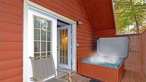 A wooden cabin with a covered outdoor seating area, a door with a window, and a bench with a heating element.