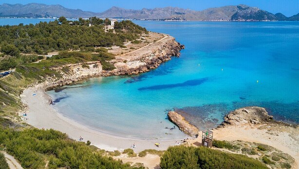 A coastal landscape with a beach, rocky shoreline, and a path leading to a building. - Villa Elvissa by Balearic Villas (Alcúdia)