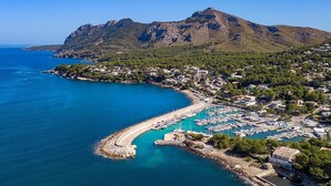 An aerial view of a coastal town with a marina, houses, and a mountain in the background. - Villa Elvissa by Balearic Villas (Alcúdia)
