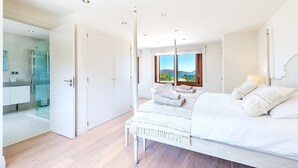 A bedroom with a bed, a window with a view, a bedside table, and a lamp. - Villa Elvissa by Balearic Villas (Alcúdia)