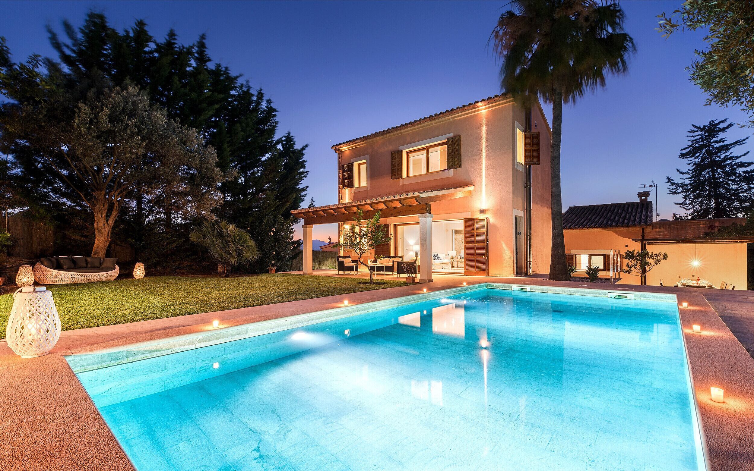 A two-story house with a swimming pool, outdoor seating area, and a well-maintained lawn.