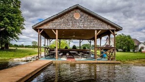 A wooden pavilion with picnic tables and a dock over water. - Pleasant Grove Inn (Linton)