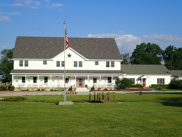A white building with a large flagpole and a star on the roof, surrounded by a well-maintained lawn. - Pleasant Grove Inn (Linton)