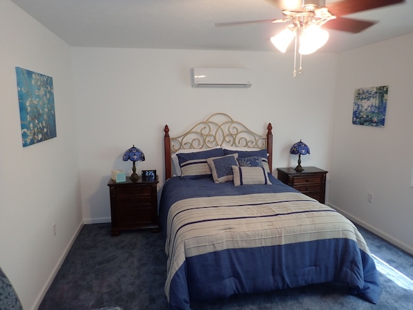 A bedroom with a bed, two bedside tables, a ceiling fan, and wall art.