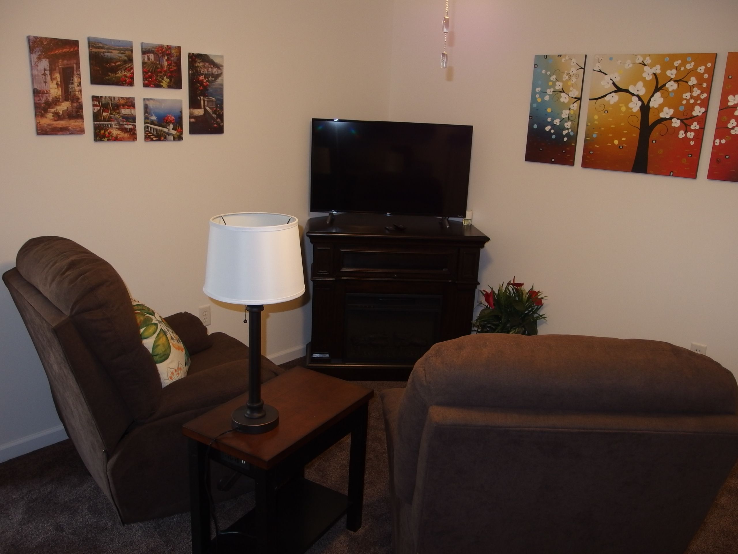 Sala de estar com televisão de tela plana, luminária, sofá e mesa pequena.
