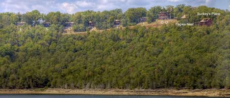 A lakeside property with numbered cabins, a boat on the water, and a view of the surrounding forest.