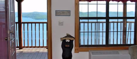 A room with a wooden deck, a view of a lake, a bear statue, and a sign on the wall.
