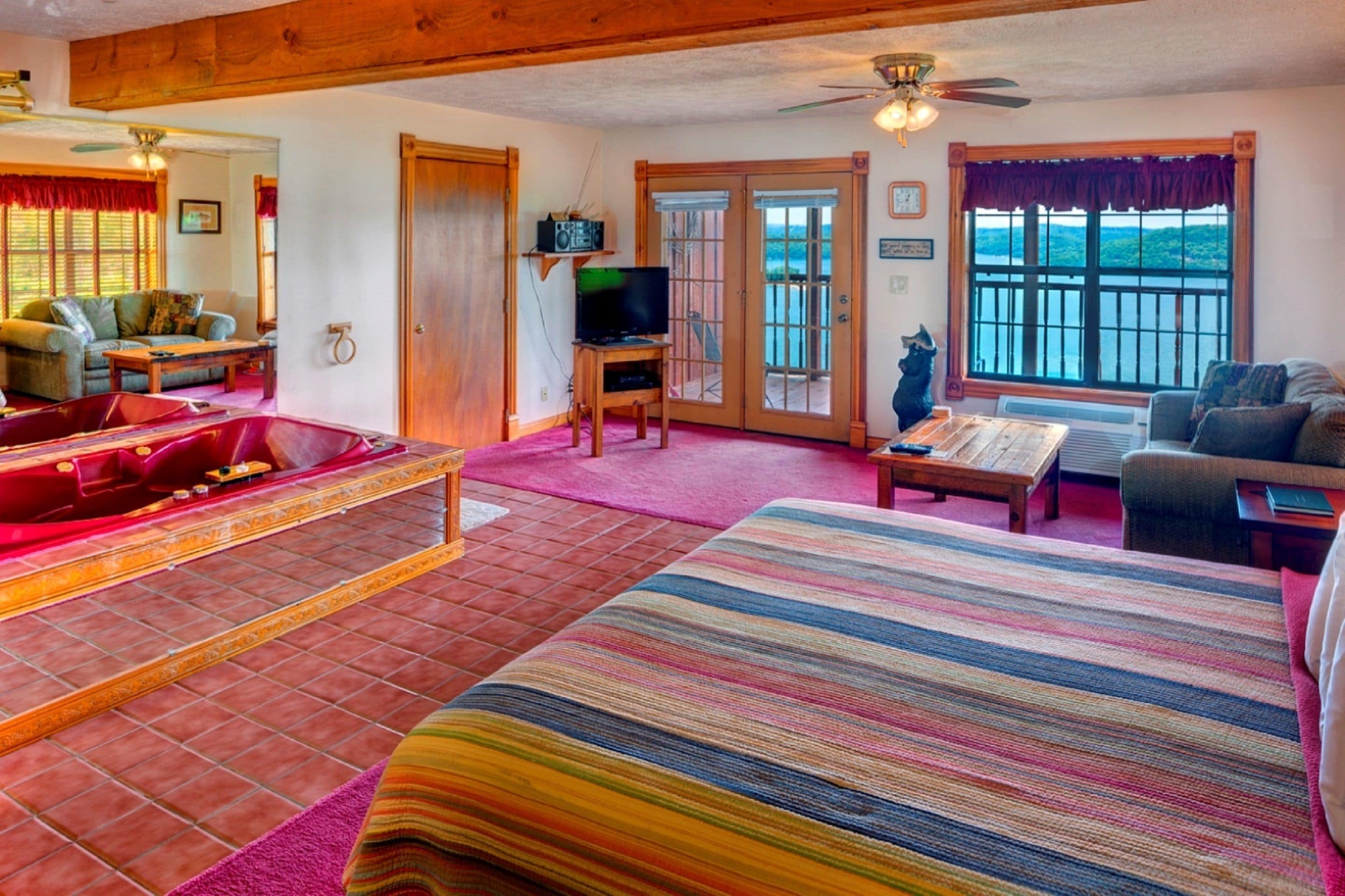 A spacious living room with a large bed, a television, a fireplace, and a view of the outdoors.