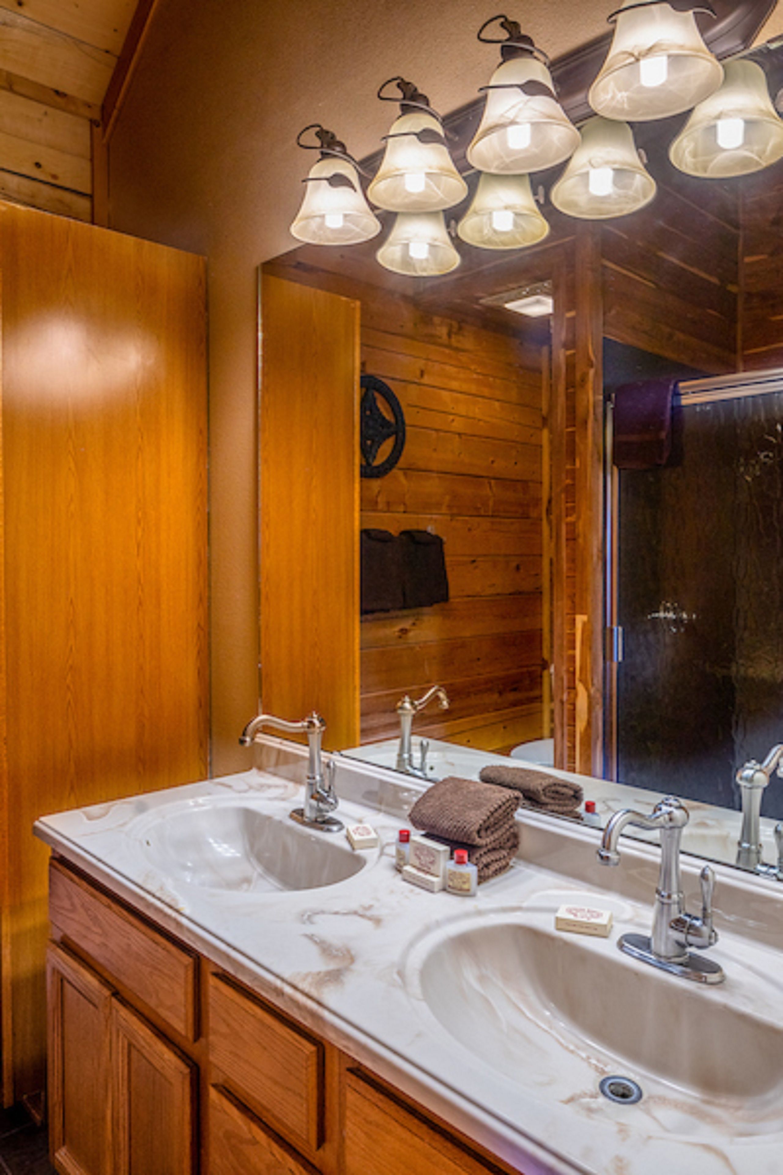 Une salle de bain avec des murs en bois, deux lavabos et un miroir.
