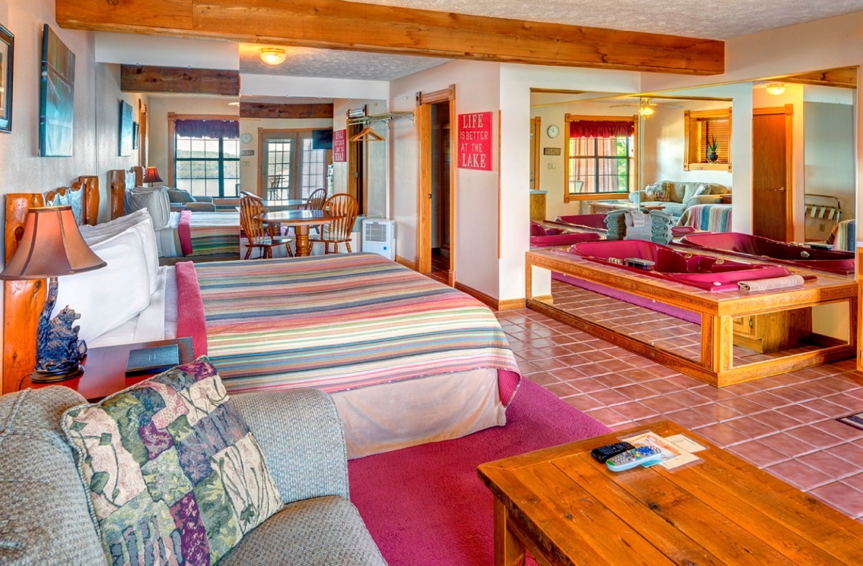 A cozy room with a large bed, a sofa, a dining table, and a wooden coffee table.