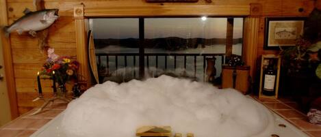 L’intérieur d’un chalet en bois, avec une grande baignoire remplie de glace, un poisson empaillé accroché au mur et une vue magnifique par la fenêtre.