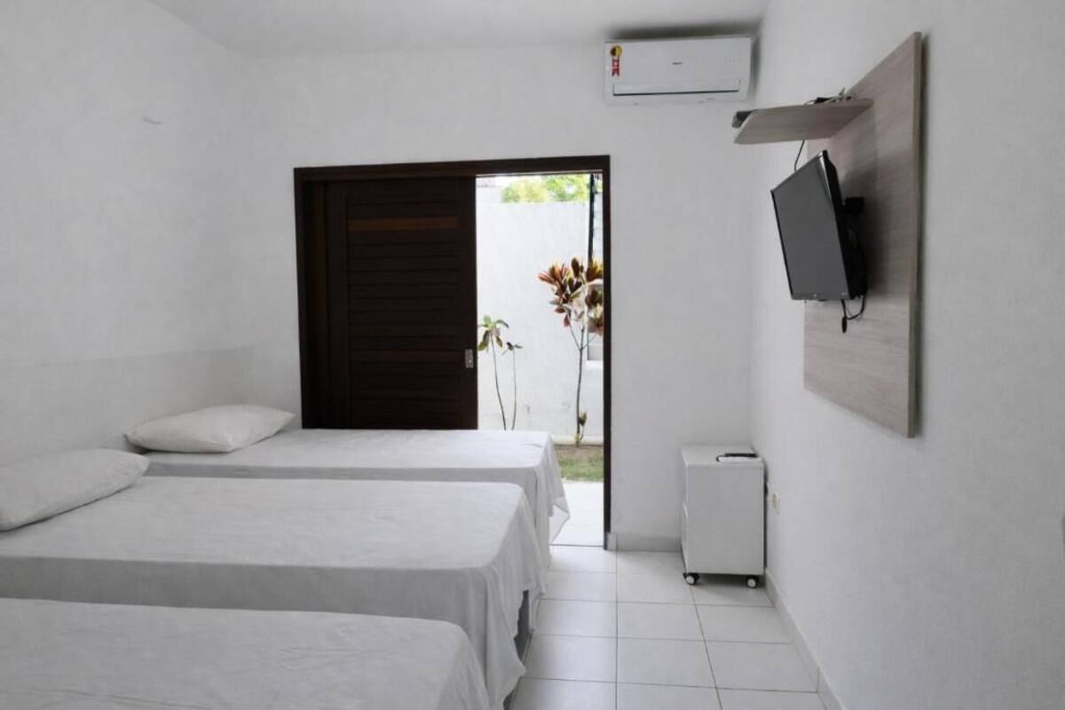 Une chambre d’hôtel avec deux lits, un téléviseur fixé au mur et un petit bureau.