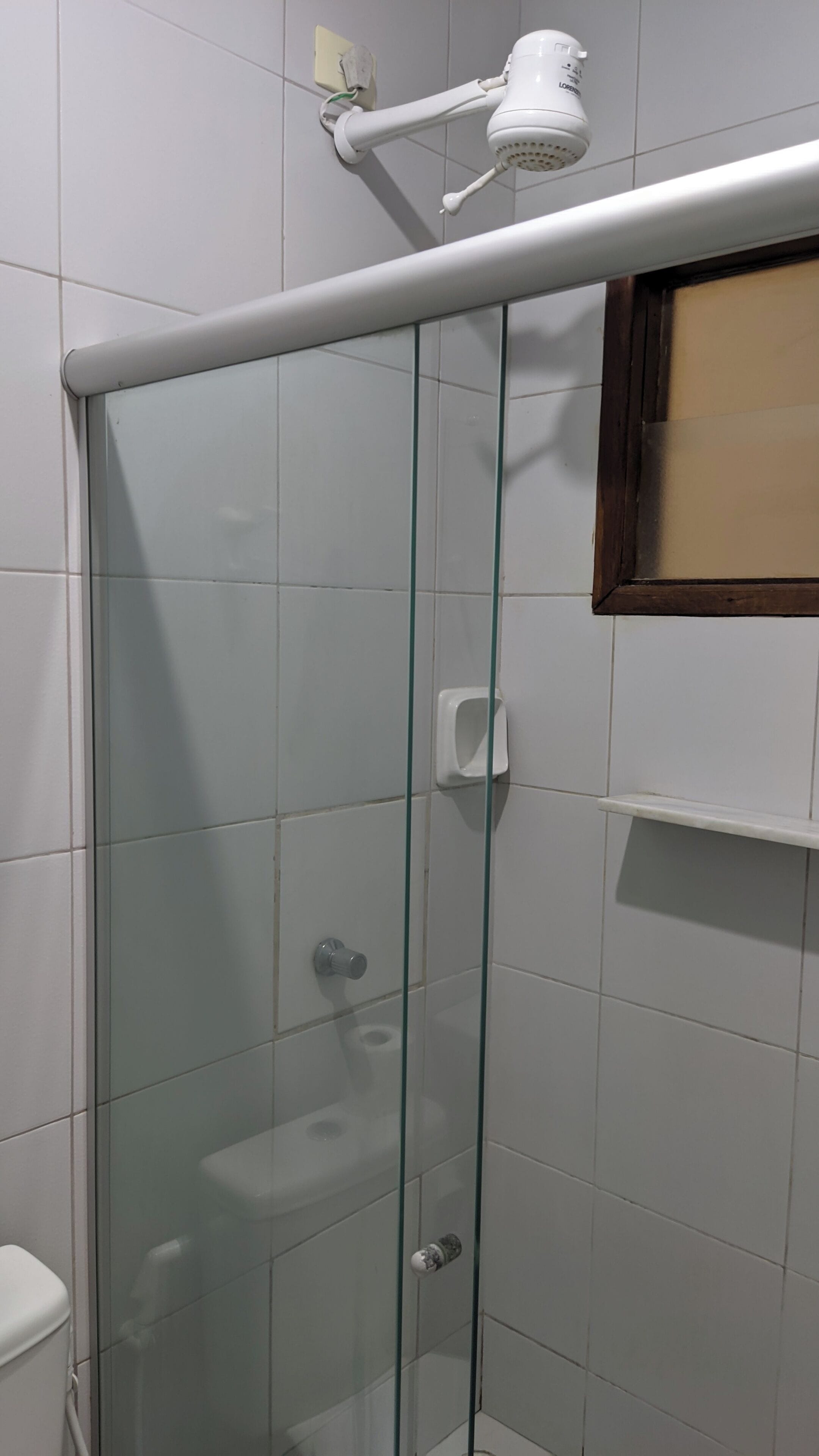 A glass-enclosed shower stall with a handheld showerhead mounted on the wall.