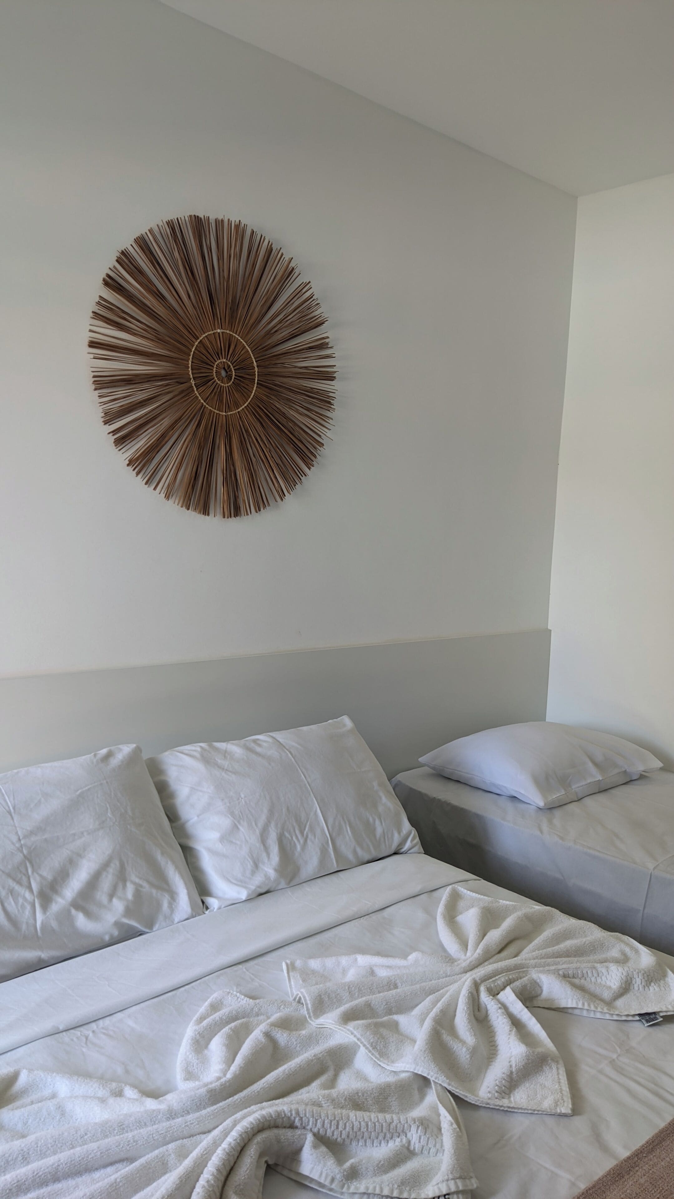 A bedroom with two beds, white bedding, and a circular wall decoration.
