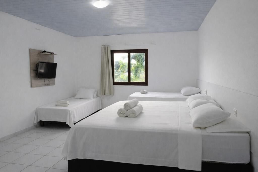Une chambre d’hôtel avec deux lits, un téléviseur à écran plat fixé au mur et une fenêtre donnant sur un paysage verdoyant.