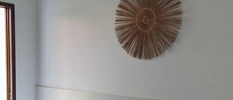 Habitación de hotel con dos camas, un adorno circular grande en la pared y una ventana a la izquierda.