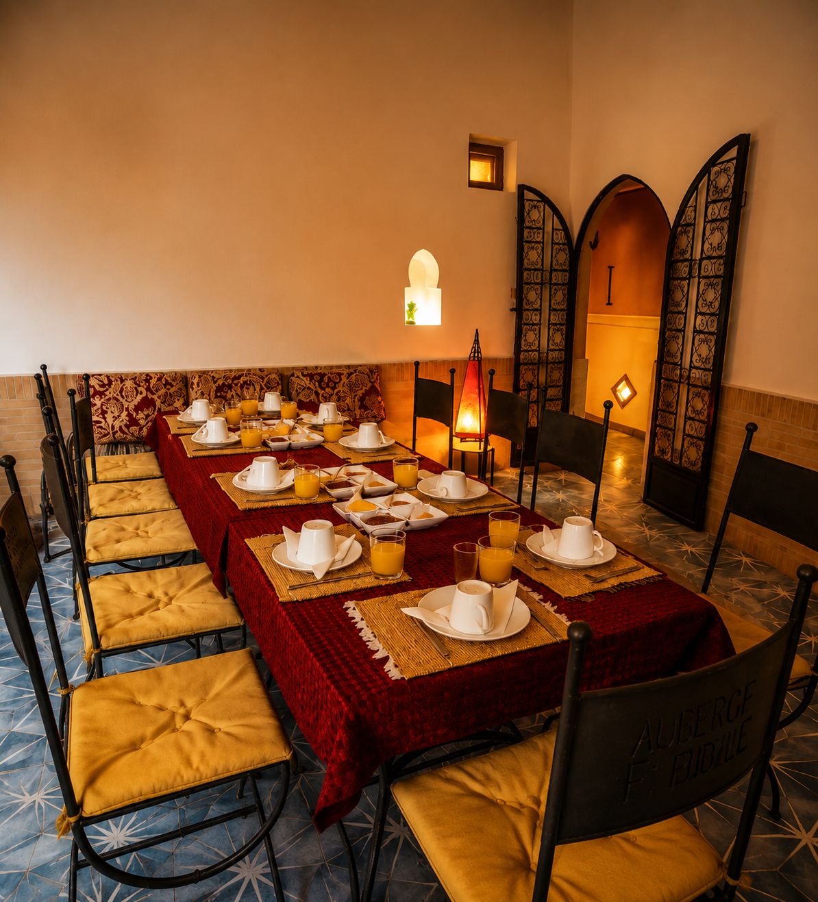 A dining area with a long table set for breakfast, including plates, cups, and glasses.