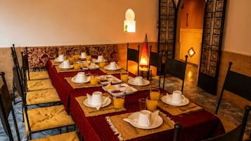 A dining area with a long table set for breakfast, including plates, cups, and glasses.