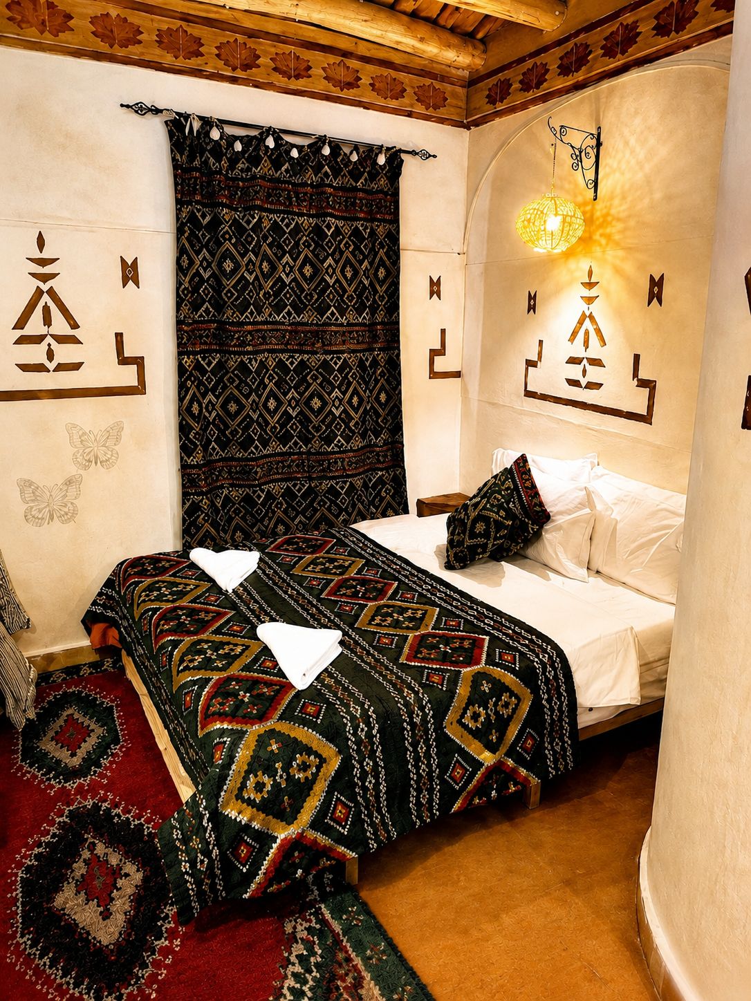 Una habitación con cama, cortinas estampadas y cuadros en la pared.