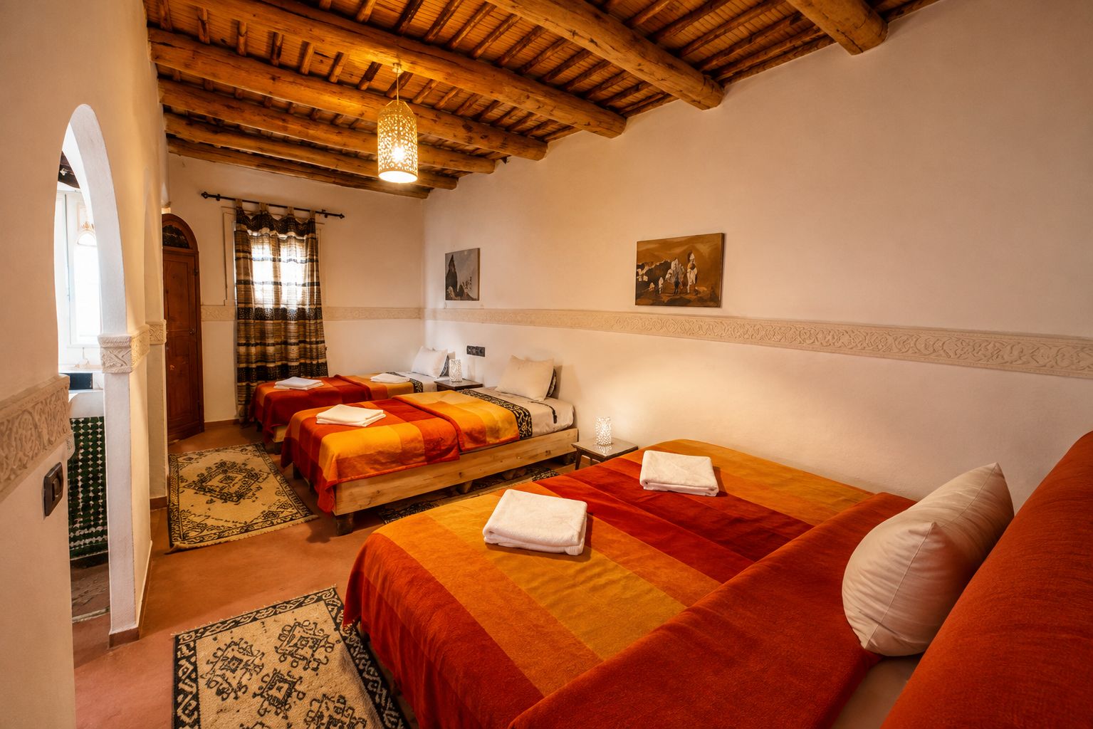 Quarto de hotel com duas camas, teto de madeira, pintura na parede e tapete estampado.